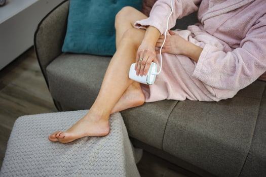 Woman removing hair with a laser device at home photo