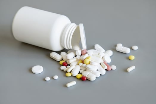 Mix of medical capsules and pills with a bottle on grey closeup. Medicinal treatment photo