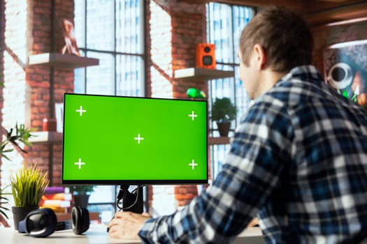 Employee seated at home office desk using green screen PC, checking emails displayed on screen, reading messages in inbox. Man managing electronic correspondence on mockup computer photo