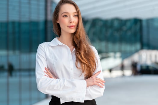 Confident businesswoman in white shirt standing arms crossed outside office photo