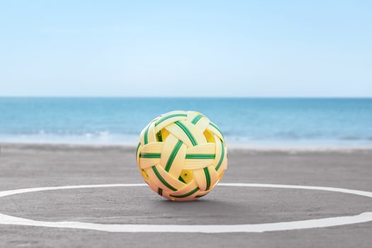 A traditional woven sepak takraw ball on a seaside court, with the calm ocean and blue sky in the background. Perfect for sports, culture, or beach lifestyle themes. photo