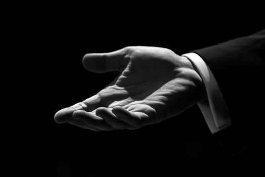 Elegant black-and-white image of an outstretched hand in a formal suit against a dark background photo