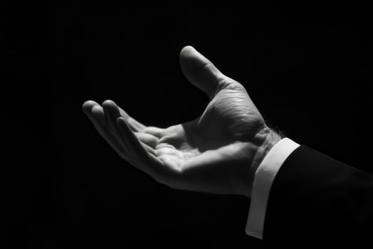Elegant hand gesture in a dark setting, symbolizing invitation or offering, with contrast photo