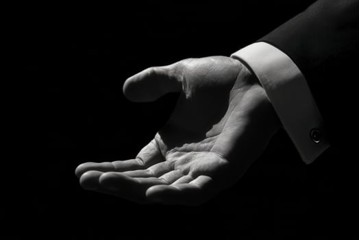 Elegant hand gesture in formal attire against a dark background, inviting and poised photo