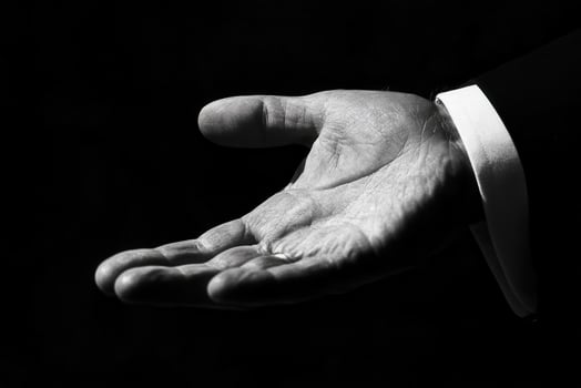 Elegant open hand gesture in black and white against a dark background, suggesting invitation photo