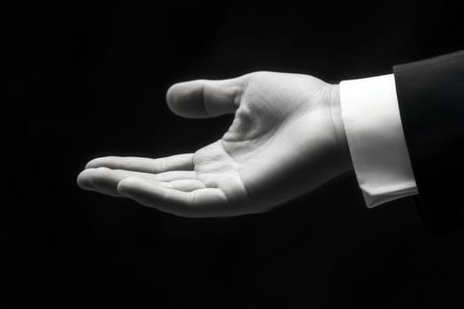 Elegant hand gesture in a business suit, showcasing an open palm against a dark backdrop photo
