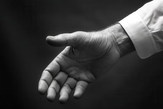 A close-up of an outstretched hand in black and white, symbolizing invitation and connection photo