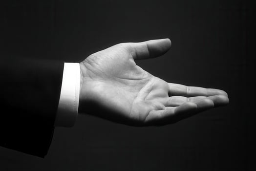 Elegant open hand gesture in formal attire against a dark background, inviting interaction photo