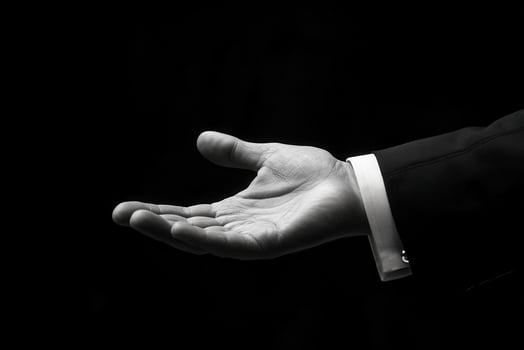 Black and white photo of a man in a suit holding out his hand