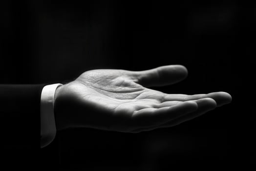 Open hand gesture in black and white, showcasing elegance and readiness in a dark setting photo