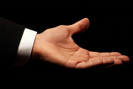 Outstretched hand in a formal setting, inviting collaboration, against a dark background photo