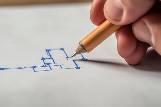 Hand holding a pencil sketching a blueprint on white paper, showcasing creative design photo