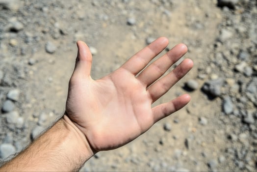 Open hand reaching out over a rocky ground, showcasing texture and natural elements photo