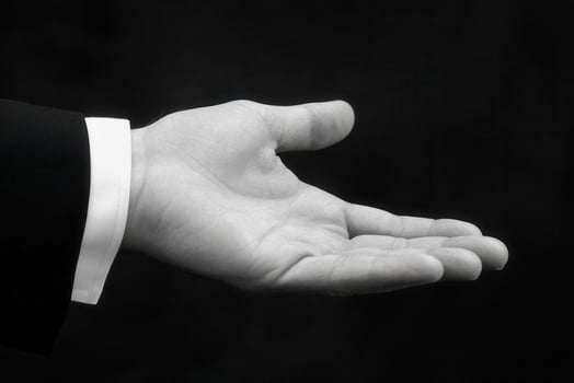Open hand gesture in a formal setting, symbolizing invitation or request, with a dark background photo