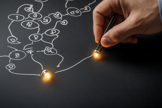 Hand tracing a complex diagram with glowing points on a chalkboard, illustrating ideas photo