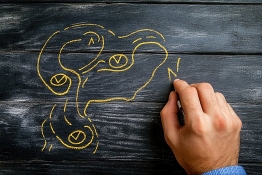 Hand drawing a creative map with yellow chalk on a rustic wooden surface, illustrating routes photo