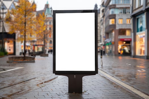 Blank advertising billboard located on a busy urban street during a rainy afternoon photo