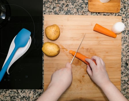 High view of chefs hands preparing and chopping vegetables. Kitchen scenery. Cooking recipe with ingredients around. Home made plate. photo