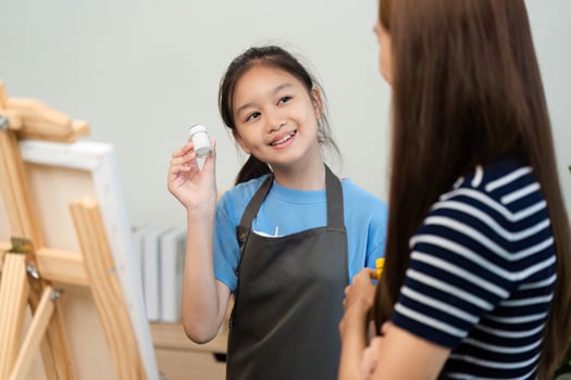 Creative Learning. Young Girl Showing Paint to Her Mentor photo