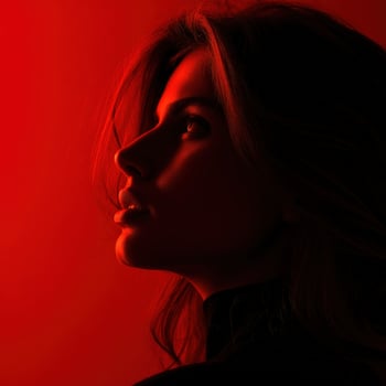 Woman with long hair poses in dramatic red light profile shot indoors photo