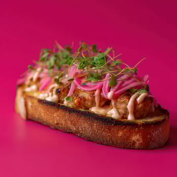 Gourmet sandwich with pink onions and microgreens on pink background photo