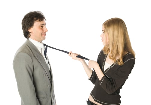 Young woman pulling a man by a necktie, isolated photo