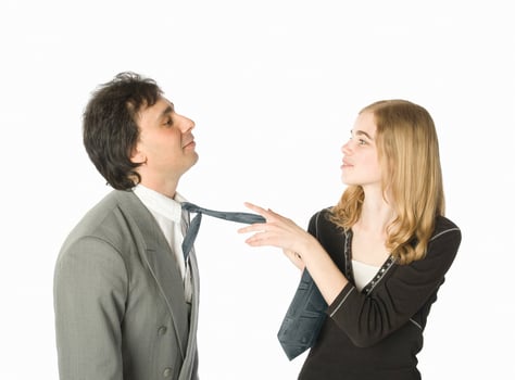 Young woman pulling a man by a necktie, white background photo