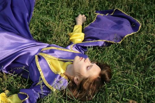 Girl in fantasy dress laying in the grass photo