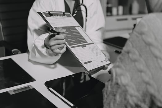 A doctor is holding a clipboard while looking at a patient photo