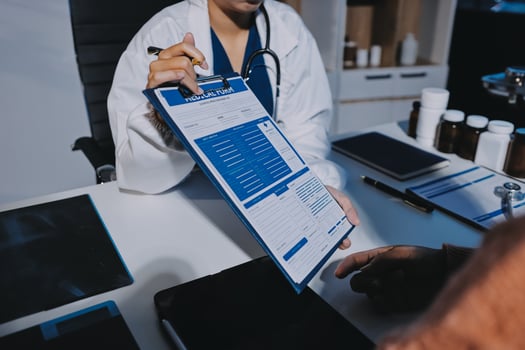 A doctor holding a clipboard while looking at a patient photo