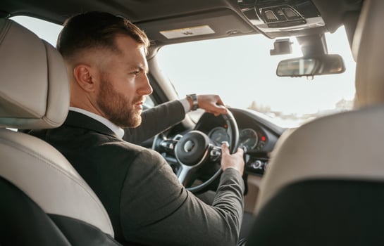 Driving,,, focused,. Man in black suit is sitting in the car, driving photo