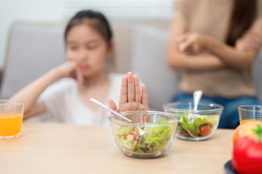 Wellness. Child refusing to eat healthy salad during mealtime photo