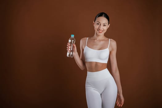 Holding bottle of water. Beautiful fitness woman is in the studio photo