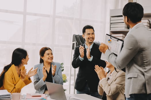 A group of business people clapping in an office photo