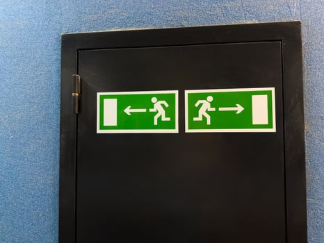 Universal exit signs with running figure and directional arrows illustrate internationally recognized emergency guidance system, offering nonverbal clarity across cultures in public buildings photo