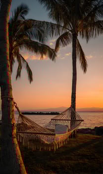 Sunset hammock scene on the tropical beach shows vacation and relaxation concept during golden hour photo