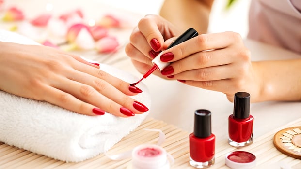 Woman receiving a professional manicure with red nail polish applied on her nails at a beauty spa setting photo