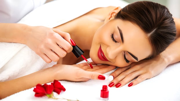 Relaxed young woman receiving a manicure at a spa beautifully painted nails with red nail polish photo