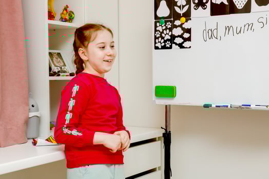 laughing little girl near magnetic board at home playing school photo