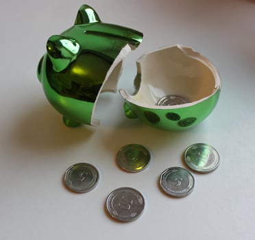 Green Ceramic Piggy Bank Cracked In Half With Coins Rolling Around photo