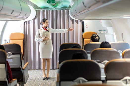 Asian flight attendant demonstrating safety procedure showing emergency exit before taking off in the airplane for cabin crew and airline business photo