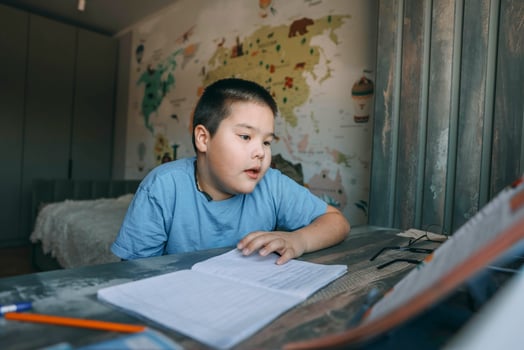 asian boy reads during homework session with geography wall map, concept of home education, e-learning, tutoring services photo