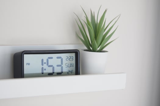 Digital clock and potted plant on a modern wall shelf at home photo