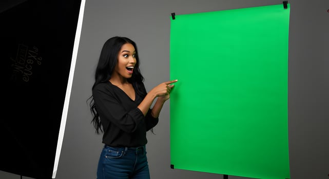 A woman pointing to a green screen photo