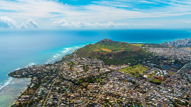 Multiple houses are built in the green valley. Diamond Head Crater and high-rise skyline at backdrop. Aerial perspective on Honolulu, Hawaii, USA photo