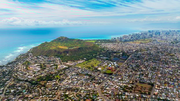 Multiple houses are built in the green valley. Diamond Head Crater and high-rise skyline at backdrop. Aerial perspective on Honolulu, Hawaii. photo