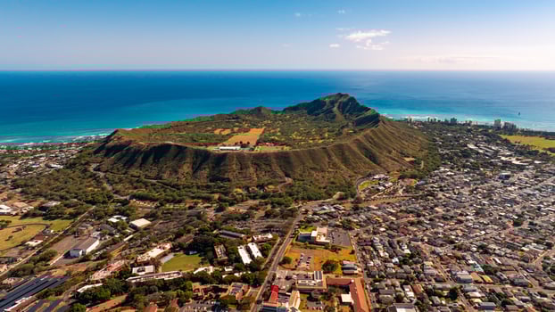 Diamond Head Crater surrounded by a modern lively cityscape. Beautiful azure waterscape at backdrop. Aerial view. photo