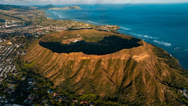 Green slope of the Diamond Head Crater. Honolulu scenery in the light of setting sun at backdrop. Aerial view. photo