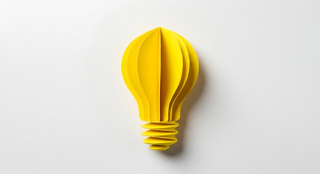 A yellow light bulb on a white surface photo