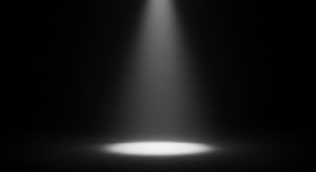 A spotlight shines on a black background photo